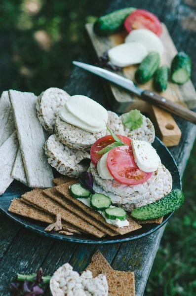 Assorted crackers and kinds of rice cake. Healthy snack with vegetables in rustic style.