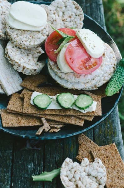Assorted crackers and kinds of rice cake. Healthy snack with vegetables in rustic style.