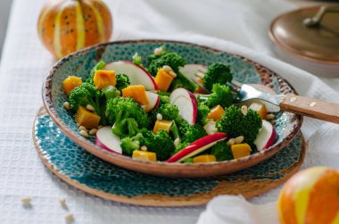 Fırında kabak, elma, brokoli ve çam fıstığı salatası. Seramik plakalar el yapımı. Rustik tarzı.