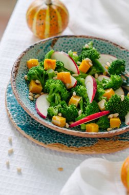 Fırında kabak, elma, brokoli ve çam fıstığı salatası. Seramik plakalar el yapımı. Rustik tarzı.