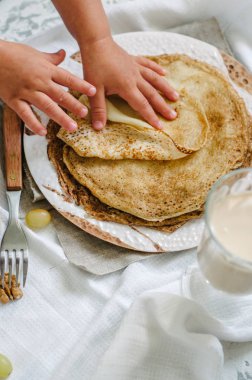 Geleneksel Ukrayna veya Rusça krep. Geleneksel yemekleri tatil karnaval Maslenitsa Shrovetide. Çocuk gözleme pişiriyor. Çocuk elinde çerçeve.