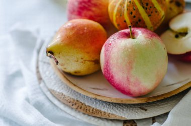 Küçük kabak, elma ve armut seramik plaka ile natürmort. Parlak renkler sonbahar natürmort. Sebze ve meyve beyaz masa örtüsü ile masada.