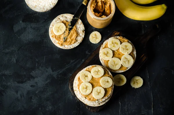 ピーナッツ バターと黒の木製テーブルの上にバナナのスライスでお餅 テキストのためのスペース — ストック写真