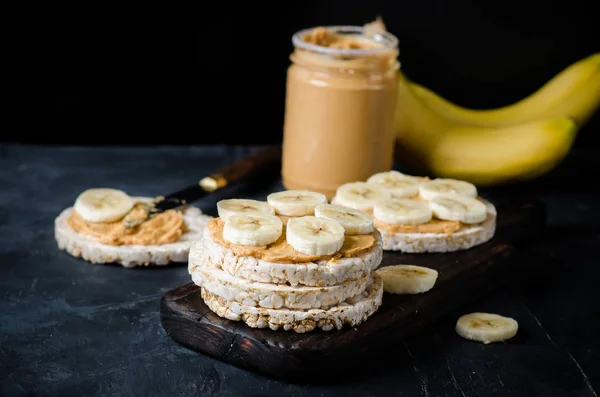 ピーナッツ バターと黒の木製テーブルの上にバナナのスライスでお餅 テキストのためのスペース — ストック写真