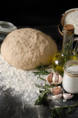 Çeşitler için malzemeler: hamur, domates, biberiye, kekik, fesleğen, zeytinyağı ahşap bir masa üzerinde.