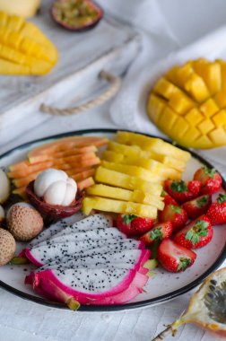 Tropikal meyve beyaz masa üzerinde birçok türde. Mangosteen, lychee, demirhindi, cherimoya, granadilla, mango, tutku meyve, rambutan, çilek, papaya.