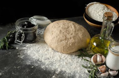 Çeşitler için malzemeler: hamur, domates, biberiye, kekik, fesleğen, zeytinyağı ahşap bir masa üzerinde.