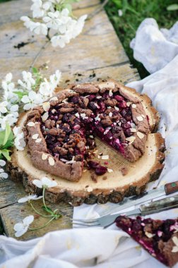 Çikolata kiraz Galette'ye veya pasta bir ahşap tahta üzerinde. Doğada bahar ya da yaz pikniği.