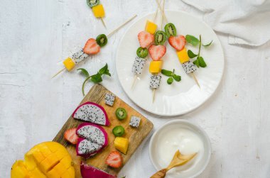 Tropikal meyve şiş-çilek, Mango, pitahaya ve mini kivi. Ahşap şiş üzerinde meyve-tatlı şiş.