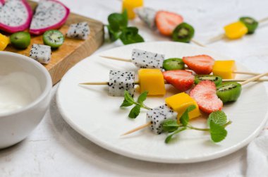Tropikal meyve şiş-çilek, Mango, pitahaya ve mini kivi. Ahşap şiş üzerinde meyve-tatlı şiş.