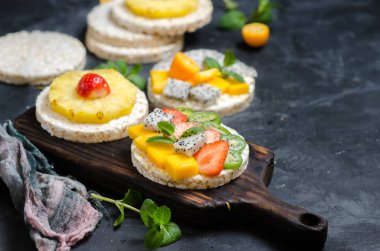 Sağlıklı kahvaltı için çilek, meyve ve yumuşak peynir ile Multigrain pirinç kek. Siyah arka plan.