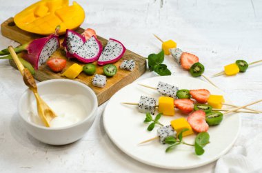 Tropikal meyve şiş-çilek, Mango, pitahaya ve mini kivi. Ahşap şiş üzerinde meyve-tatlı şiş.