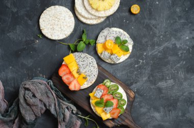 Sağlıklı kahvaltı için çilek, meyve ve yumuşak peynir ile Multigrain pirinç kek. Siyah arka plan. Üst görünüm.