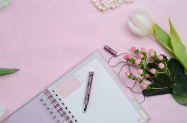 Beyaz ve pembe renkler, çiçekler, kalem, kozmetik ve hediye kutuları ile dizüstü kadın aksesuarları. Güzellik kadınları düz yatıyordu. Üst görünüm, metin alanı.