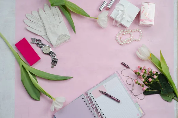 Women's accessories in white and pink colors, flowers, notebook with pen, cosmetics and gift boxes. Beauty women flat lay. Top view, space for text.