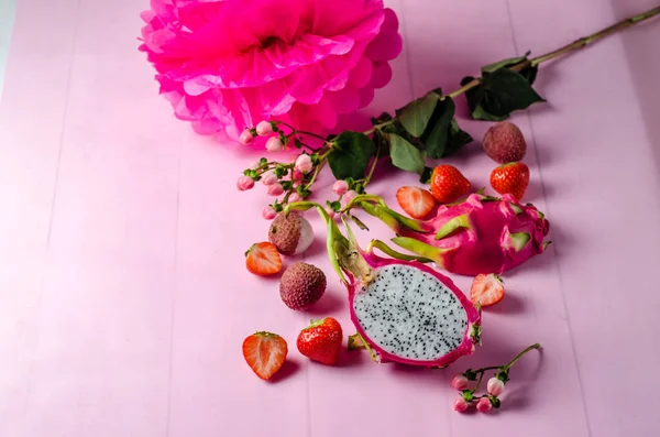 Trendy fruit set on a bright pink background, dragon fruit, lychee, strawberry. Pink women flat lay.