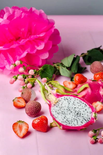 Trendy fruit set on a bright pink background, dragon fruit, lychee, strawberry. Pink women flat lay.