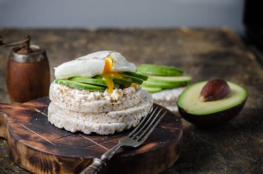 Krem peynir, avokado ve siyah arka plan üzerinde haşlanmış yumurta ile Pirinç kek. Sandviçli sağlıklı kahvaltı.