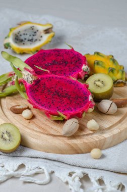 Çeşitli ejderha meyve - sarı ve kırmızı pitahaya, sarı kivi ve fındık ahşap bir tepsi üzerinde