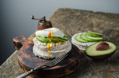 Krem peynir, avokado ve siyah arka plan üzerinde haşlanmış yumurta ile Pirinç kek. Sandviçli sağlıklı kahvaltı.