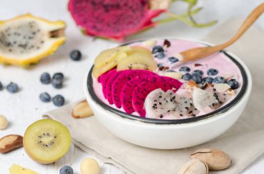 Sağlıklı kahvaltı kaseyemek. Smoothie whith kırmızı ve sarı ejderha meyve, sarı kivi ve yaban mersini beyaz seramik kase.