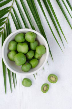 Beyaz tabakta mini kivi. Beyaz arka planda küçük egzotik meyveler.