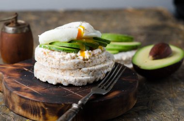 Krem peynir, avokado ve siyah arka plan üzerinde haşlanmış yumurta ile Pirinç kek. Sandviçli sağlıklı kahvaltı.