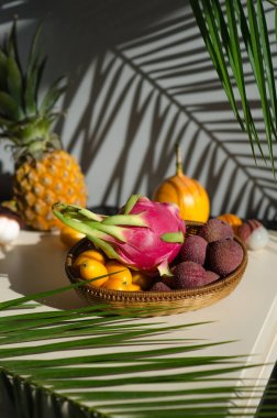 Masadaki tabaklarda çeşitli tropikal meyveler bulunur. Ejderha meyve kumquat, pitahaya, ananas, granadilla, lychee, tutku meyve. masada palmiye yaprakları