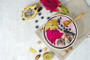 Sağlıklı kahvaltı kaseyemek. Smoothie whith kırmızı ve sarı ejderha meyve, sarı kivi ve yaban mersini beyaz seramik kase.