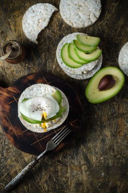 Krem peynir, avokado ve siyah arka plan üzerinde haşlanmış yumurta ile Pirinç kek. Sandviçli sağlıklı kahvaltı.
