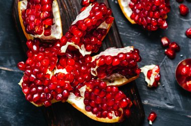 Nar koyu bir arka plan üzerinde kırmızı tanecikleri ile parçalara ayrılmış.