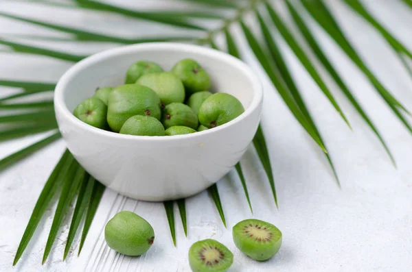 Mini kiwi en un plato blanco. Pequeñas frutas exóticas sobre fondo blanco . —  Fotos de Stock