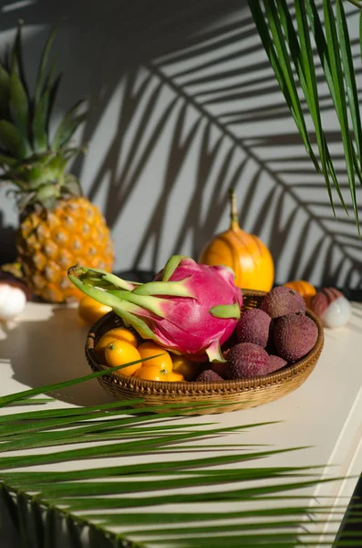 Masadaki tabaklarda çeşitli tropikal meyveler bulunur. Ejderha meyve kumquat, pitahaya, ananas, granadilla, lychee, tutku meyve. masada palmiye yaprakları