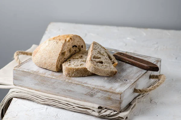 Свежий хлеб и нарезанный хлеб на деревенском деревянном столе — стоковое фото