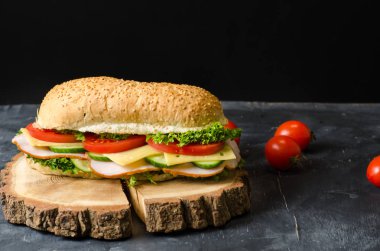 Siyah arka plan üzerinde ahşap bir tahta üzerinde jambon, peynir, domates ve salata ile lezzetli sandviçler. Metin için alan