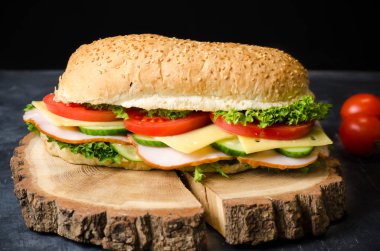 Siyah arka plan üzerinde ahşap bir tahta üzerinde jambon, peynir, domates ve salata ile lezzetli sandviçler