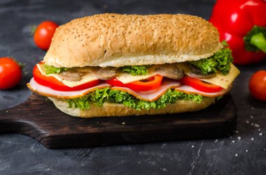 Taze sebze dolu ahşap bir masada jambon, peynir, kırmızı biber, mantar ve salata ile lezzetli sandviçler.