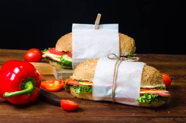 Ahşap bir masada sebze, peynir, jambon, salam ve salata ile sandviç sağlıklı ev yapımı atıştırmalık veya öğle yemeği. Metin için alan