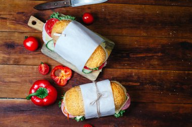 Ahşap bir masada sebze, peynir, jambon, salam ve salata ile sandviç sağlıklı ev yapımı atıştırmalık veya öğle yemeği. Metin için boşluk. Üstte görüntü.