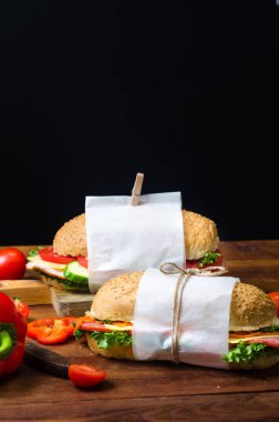 Ahşap bir masada sebze, peynir, jambon, salam ve salata ile sandviç sağlıklı ev yapımı atıştırmalık veya öğle yemeği. Metin için alan