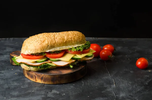 美味的三明治，火腿，奶酪，西红柿和沙拉在黑色背景的木板上。文本空间 — 图库照片