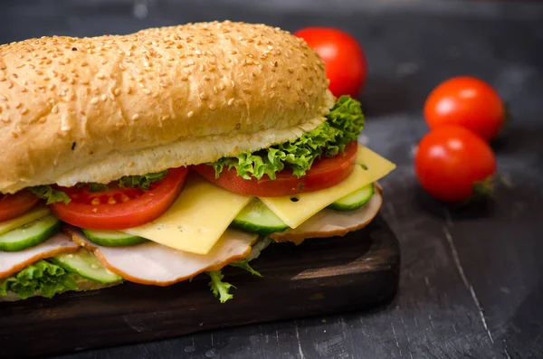 美味的三明治，火腿，奶酪，西红柿和沙拉在黑色背景的木板上 — 图库照片