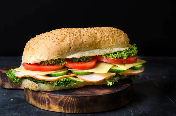 美味的三明治，火腿，奶酪，西红柿和沙拉在黑色背景的木板上 — 图库照片