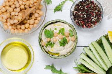 Çeşitli aperatifler ile humus tabağı. Kasede humus, sebze çubukları, nohut, zeytinyağı. Sebzeler, humus sosu, kopya alanı. Üst te. Beyaz ahşap arka plan