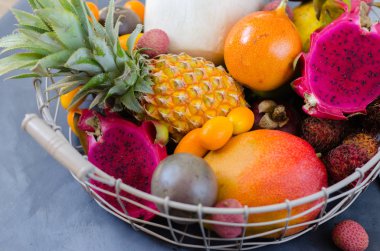 Sağlıklı beslenme, metal bir sepet içinde egzotik meyve çeşitleri. Tropikal meyveler bütün ve dilimlenmiş.