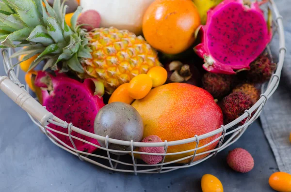 Hälsosam kost, variiteten av exotiska frukter i en metall korg. Tropiska frukter hela och skivade. — Stockfoto