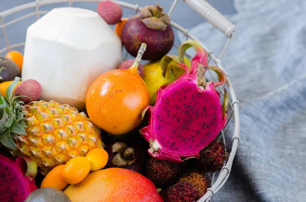 Hälsosam kost, variiteten av exotiska frukter i en metall korg. Tropiska frukter hela och skivade. — Stockfoto