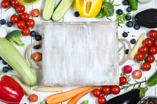 Каркас Асорті зі свіжих овочів на білому дерев'яному фоні. Дерев'яна обробна дошка. Місце для тексту — стокове фото