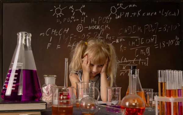 Curious little girl with test tubes and colorful substances makes tests at school laboratory. Small kid learning chemistry and conducts science experiment on biology lesson. Future microbiologist.