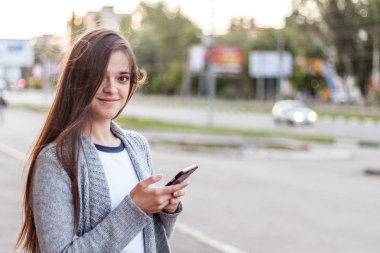 Yaz gününde sokak City'deki onun smartphone kullanarak gülümseyen longhair kız